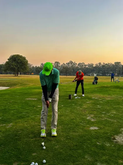 A golfer in a bright green hat lines up his shot, adding a pop of color to the range.