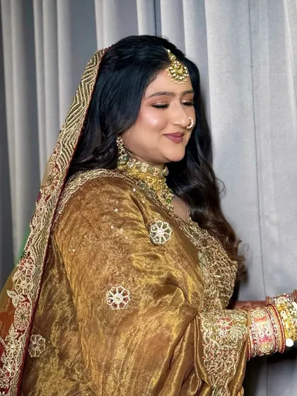 A side view of the bride, highlighting the details of her dupatta and the soft curls in her hair.