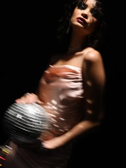 A close-up from the disco series, with dramatic shadows and a pop of light from the disco ball. This highlights the model's expression and the texture of the dress.