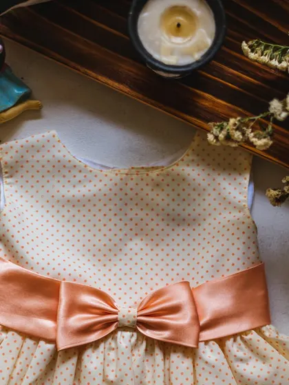 A playful polka dot dress with a sweet peach bow, perfect for rocking and rolling in style.