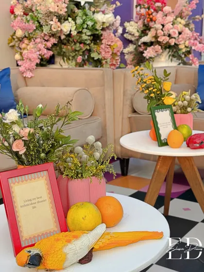 Every detail is an opportunity for storytelling. This table setting features a ceramic parrot, fresh fruits, and framed quotes, creating a small, curated world for guests to discover.