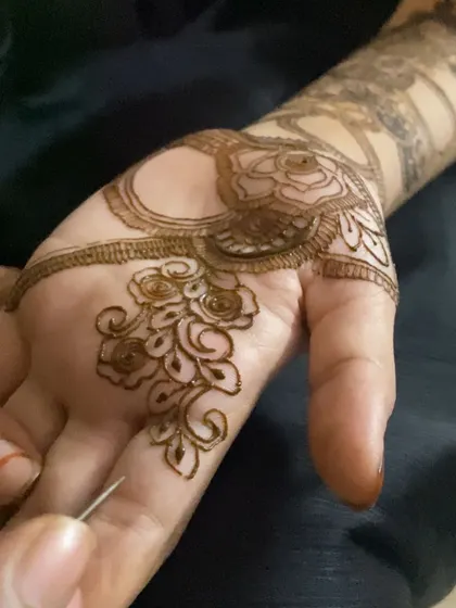 A close-up of me working on a delicate rose pattern in the palm. The fine lines and careful application are key to achieving this soft and romantic floral look.