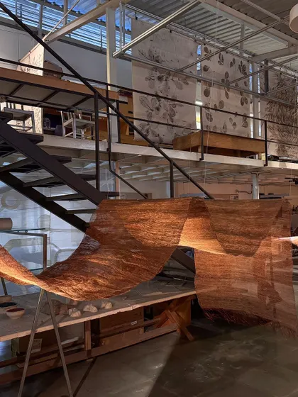 A view of the 'Cu+Fibers' installation from our studio's mezzanine level. The flowing, semi-transparent woven sculpture interacts with the industrial architecture of the space.