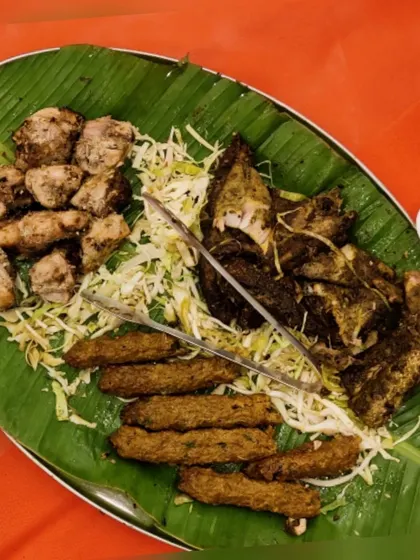A classic starter platter served on a traditional banana leaf. It features tender sheesh kebabs, grilled fish, and malai chicken pieces, showcasing a variety of textures and authentic flavours.