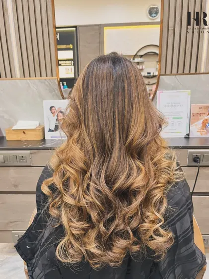 A beautiful and dramatic balayage with a high contrast between the dark roots and light, curly ends.