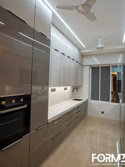 A view of the tall unit in a lacquered glass kitchen, with a built-in oven. We design our kitchens to integrate appliances perfectly for a streamlined and cohesive appearance.