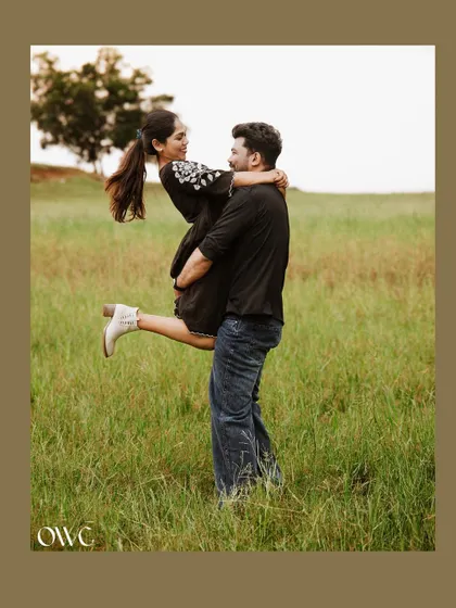 A beautifully framed shot of the groom lifting his bride-to-be in a field, creating a classic romantic portrait.