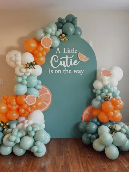 "A Little Cutie is on the way" baby shower theme. The mix of orange, teal, and white balloons with citrus details creates a fresh, contemporary, and playful vibe.