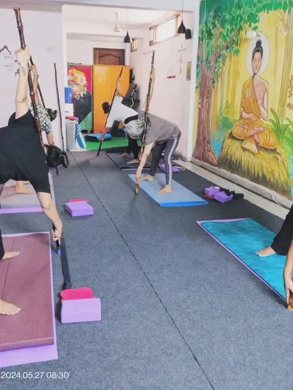 In some sessions, we use props like sticks to assist with alignment and deepen stretches. Here, students are using them to get a better opening in a standing forward bend variation.
