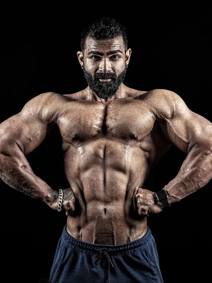 A front lat spread pose, again using dramatic lighting to emphasize the width and V-taper of the torso.