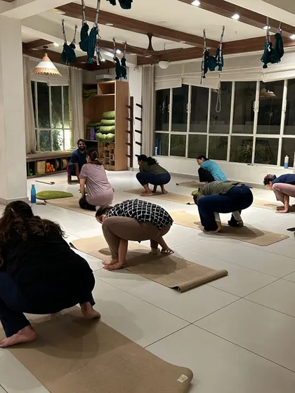 Students practice a deep squat, a foundational pose for hip mobility and grounding.