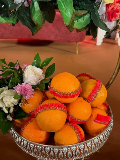 A simple yet elegant fruit basket of oranges. Each fruit is decorated with a red lace ribbon, showing how small details can elevate the entire presentation.