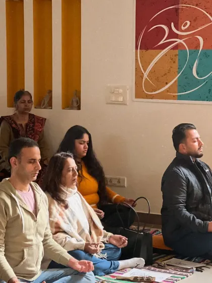 A group of participants engaged in a meditation session at our centre. The 'Om' artwork on the wall serves as a constant reminder of the universal sound and our connection to it.