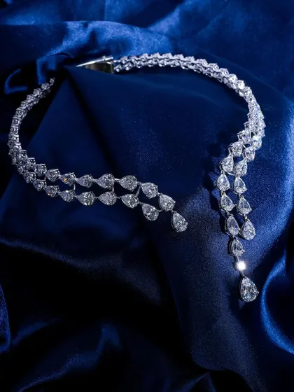 This cascading diamond necklace is draped beautifully on a rich blue satin cloth, highlighting its fluid design and incredible sparkle. A truly showstopping piece.
