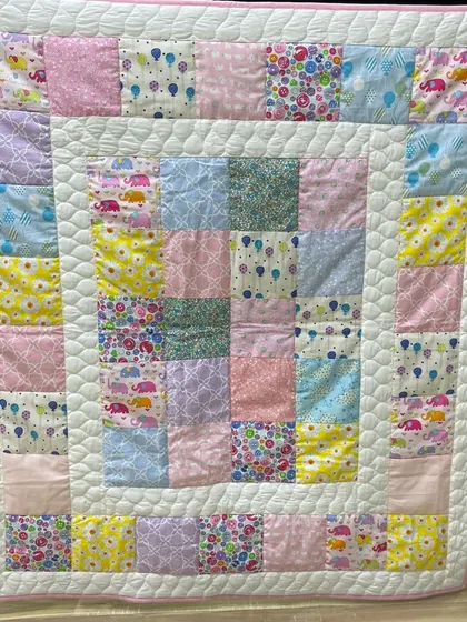 A soft, pastel-colored baby quilt with a simple patch design, perfect for a nursery.