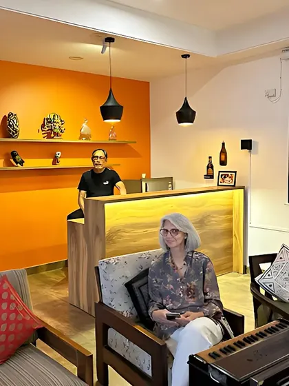 Our clients enjoying their newly designed private den. The space combines a vibrant orange accent wall with warm wood tones and modern black pendant lights to create an energetic and welcoming atmosphere.