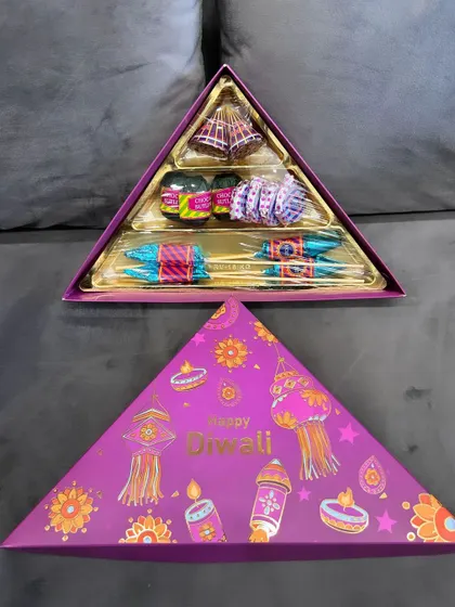 This unique triangle-shaped Diwali gift box is filled with an assortment of firecracker chocolates. The vibrant packaging and fun contents make it a memorable festive present.
