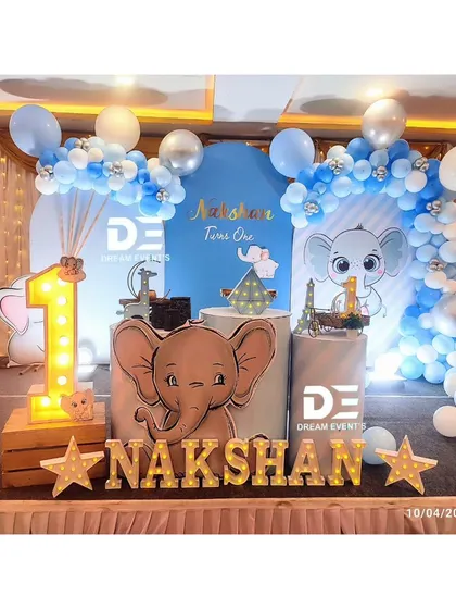 Another view of Nakshan's elephant-themed party, highlighting the light-up number '1' and the arrangement of props on the stage.