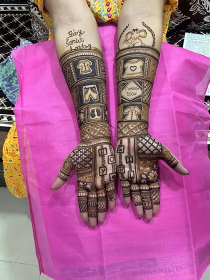 A closer look at the details in this custom Godh Bharai mehndi. You can clearly see the baby clothes, the 'Coming Soon' message, and the playful 'Baby Loading' text on the forearm.