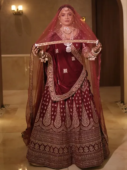 A full-length shot of this magnificent bride in her velvet maroon lehenga. The entire look is styled to create a royal and timeless bridal portrait.