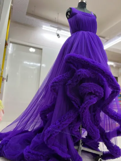 A side view of the dramatic purple gown, showing the one-shoulder design and the voluminous trail.