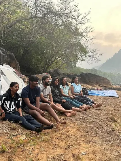 A group of friends relaxing at the campsite as the sun sets.