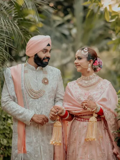 A candid, loving portrait of Simran and Sanjit, their pastel pink and white outfits perfectly suited for a daytime Anand Karaj.