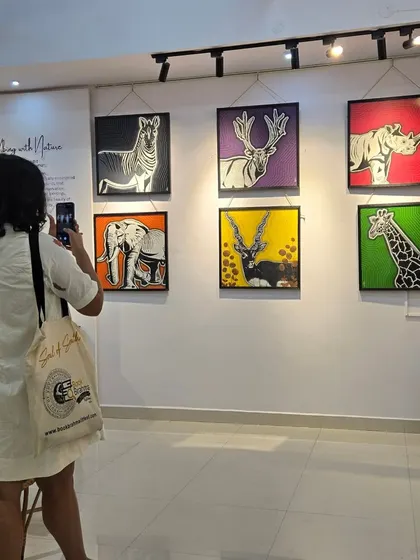 A visitor at our "Vibing with Nature" exhibition takes a photo of the colorful animal portraits by artist Puja Kumari. The series features endangered animals in a bold, graphic style.