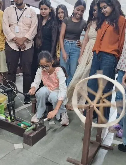 A student gets a chance to try her hand at spinning yarn on a traditional charkha during the visit to the Weaver's Service Centre.