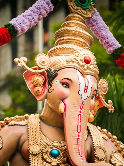A detailed close up of a beautifully decorated Ganesh idol. I focused on the intricate artwork on the idol's face and the vibrant colors of the garlands.