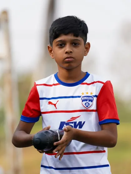 A young athlete holds a water bottle, a reminder of the importance of hydration, which is a key part of our training regimen.