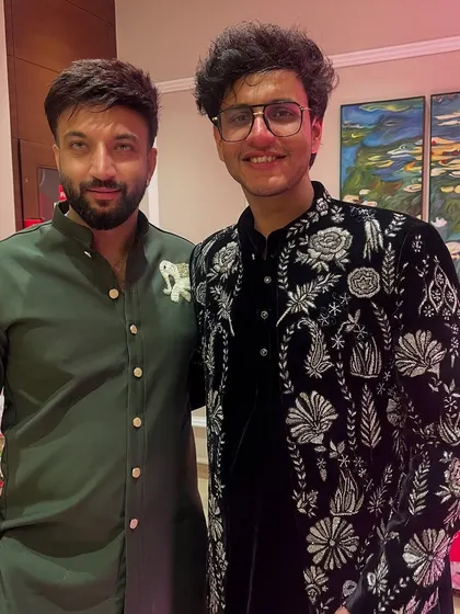 Another view of the custom black velvet sherwani with detailed white and silver floral embroidery, designed for a celebrity client's wedding.