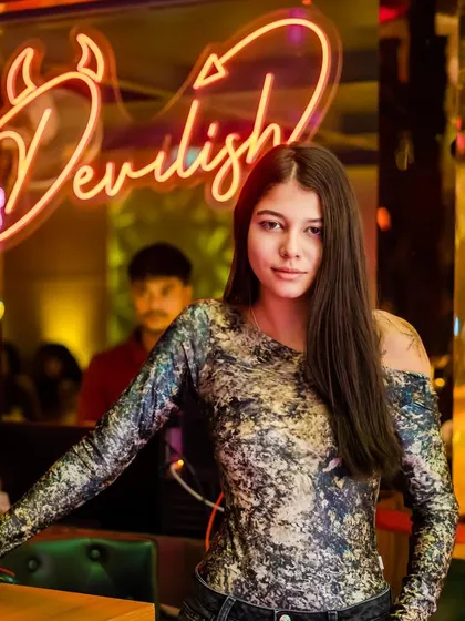 A guest posing in front of the neon 'Devilish' sign. The decor at the venues I play adds to the overall party experience.