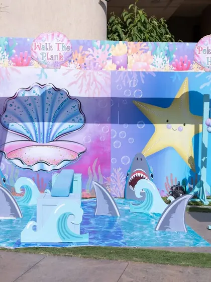 An interactive "Walk The Plank" game setup for an Under the Sea party, complete with friendly sharks and ocean waves for a fun photo opportunity.