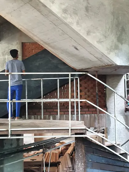 A construction worker on a temporary staircase at the Brick House site, with the complex geometry of the final staircase beginning to take shape.