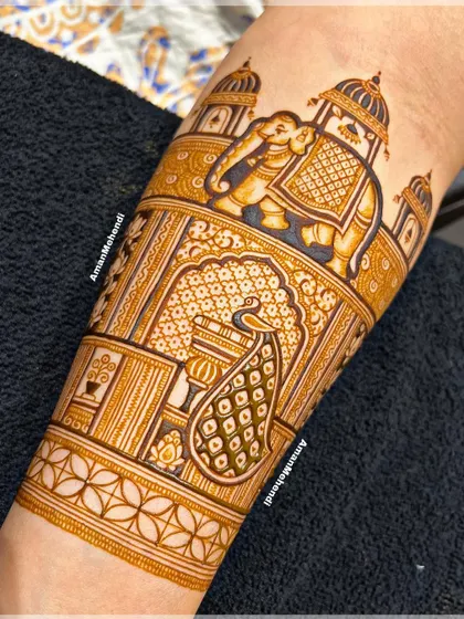 A detailed view of a bridal arm piece. This section features a royal elephant in front of a palace, with a beautiful peacock figure below it.