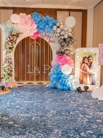 A wide view of the Baby Dior shower setup, showing the various decor elements like the cradle, marquee letters, and balloon arch.