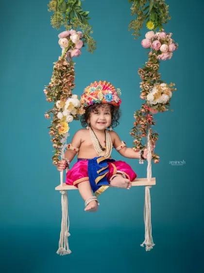 Watch your little one's joy in this playful Janmashtami setup. Dressed as baby Krishna, your child will have fun on a beautifully decorated floral swing, creating cheerful and divine portraits.