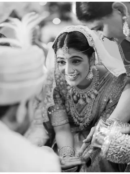 A beautiful black and white candid of the bride's smiling face during a wedding ritual.