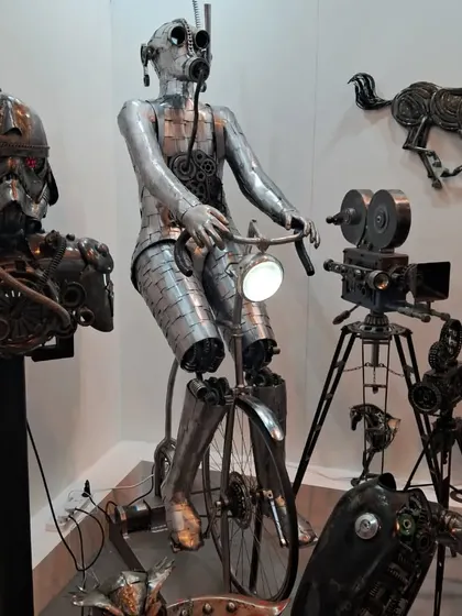 A collection of futuristic metal sculptures, including a stormtrooper-like bust and a robotic figure on a bicycle.