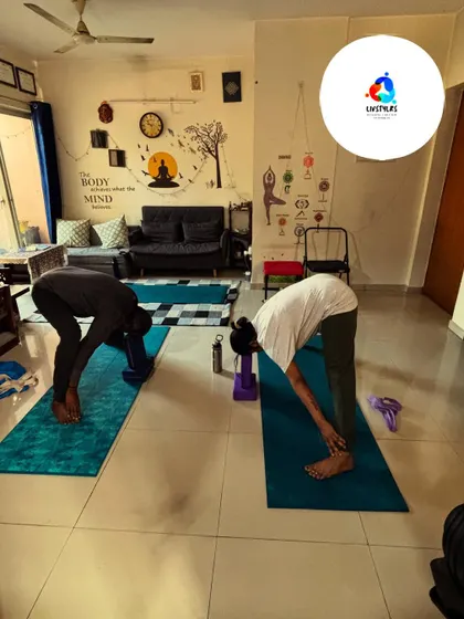 Two clients perform a standing forward bend (Uttanasana) with support from yoga blocks. This helps them achieve a deeper stretch in the hamstrings and lower back without compromising form.