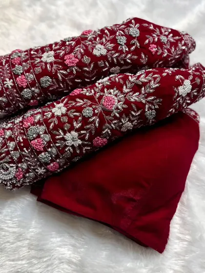 A client's order for a red velvet bridal blouse material, with sleeves heavily embroidered in silver and pink floral patterns.