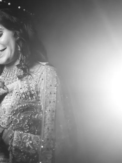 A black and white version of a candid bridal moment. The lack of color emphasizes her joyful expression and the beautiful textures of her sparkling dress and jewelry.
