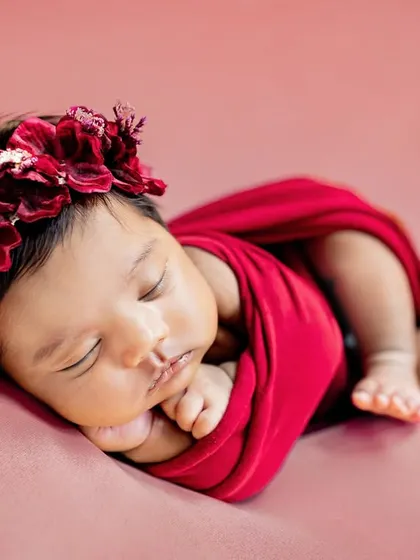 This little one looks like a beautiful rose, wrapped in red with a delicate floral crown. I use a variety of colorful wraps and props to style your newborn session.