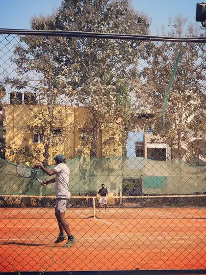 A view through the fence of a player hitting a backhand during the Men's Open Tour.