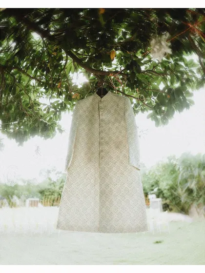 A duplicate of the groom's sherwani hanging from the tree, a great detail shot.