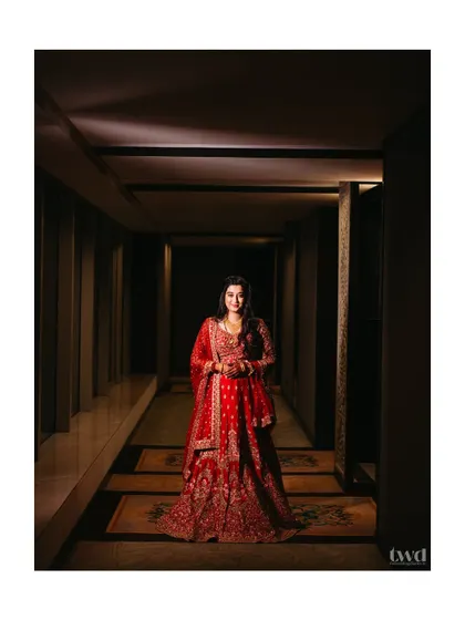 Draped in red, glowing with elegance. This portrait captures the bride's regal reception look in a beautifully lit hotel corridor, making her look like royalty.