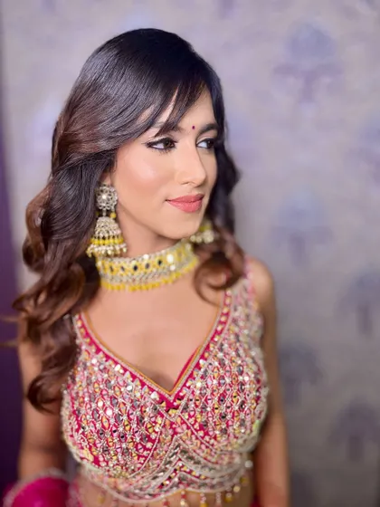 A beautiful side profile, highlighting the soft waves in her hair and the flawless finish of her makeup.