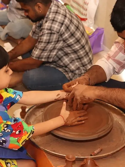A father and daughter work together on the pottery wheel. This tactile activity is a wonderful introduction to physics, demonstrating how force and motion can shape clay into a vessel.