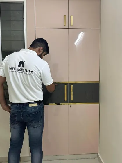 This two-tone wardrobe combines a blush pink high-gloss finish with a dark grey accent panel and gold T-profile inlays. It's a great example of how mixing materials can create a unique look.